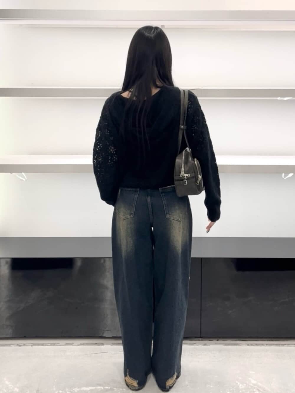 ホワイト系のスニーカー、ブルー系のデニムパンツ、ブラック系のパーカーを着用したレディースの春コーディネートの3枚目の写真