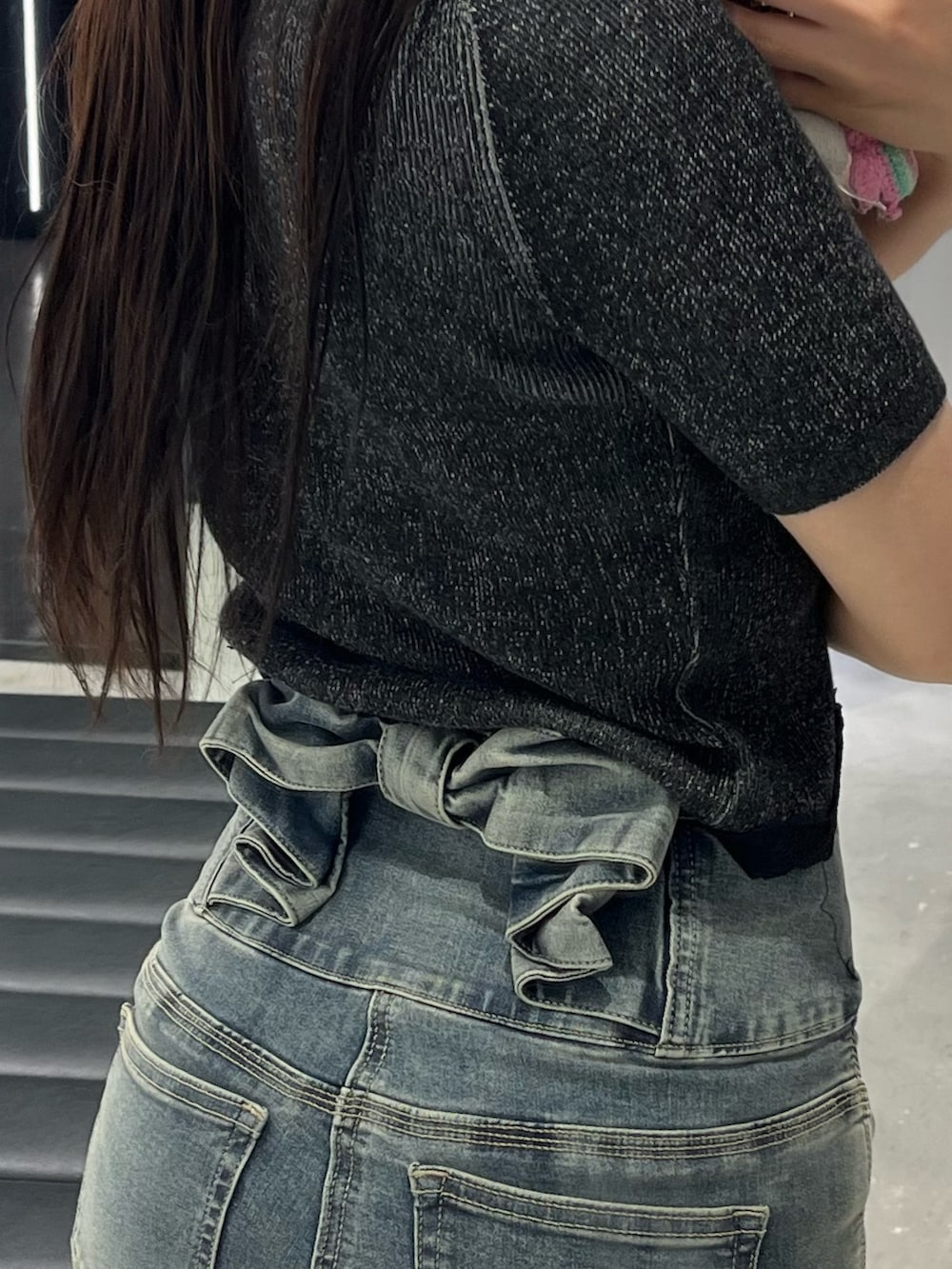 ブラック系のニット/セーター、ブルー系のデニムパンツ、ブラック系のサンダルを着用したレディースの春コーディネートの6枚目の写真