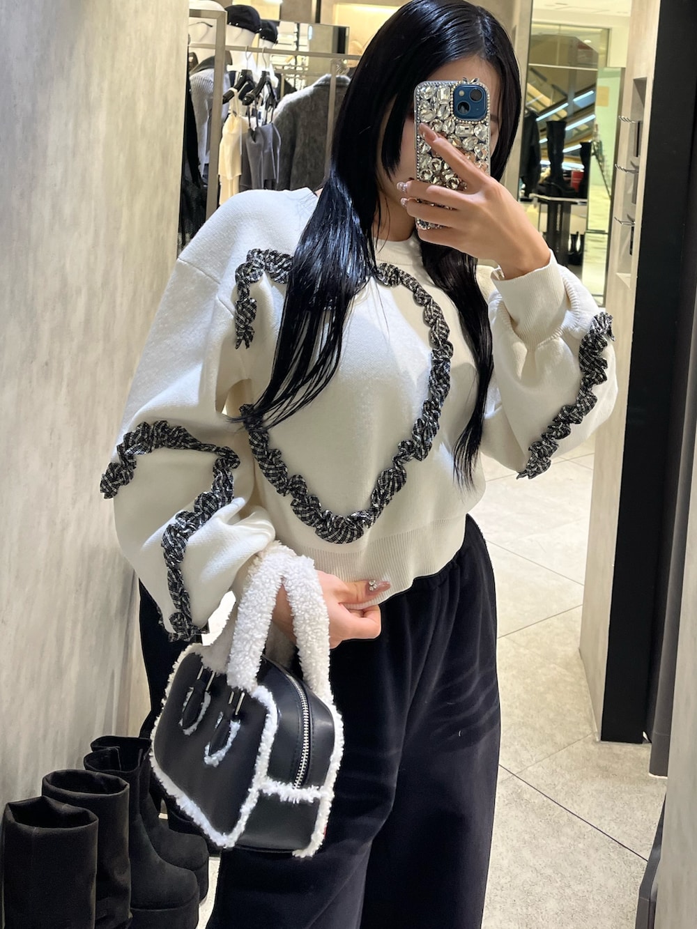 ホワイト系のニット/セーター、ブラック系のスウェットパンツ、ブラック系のハンドバッグを着用したレディースの冬コーディネートの5枚目の写真