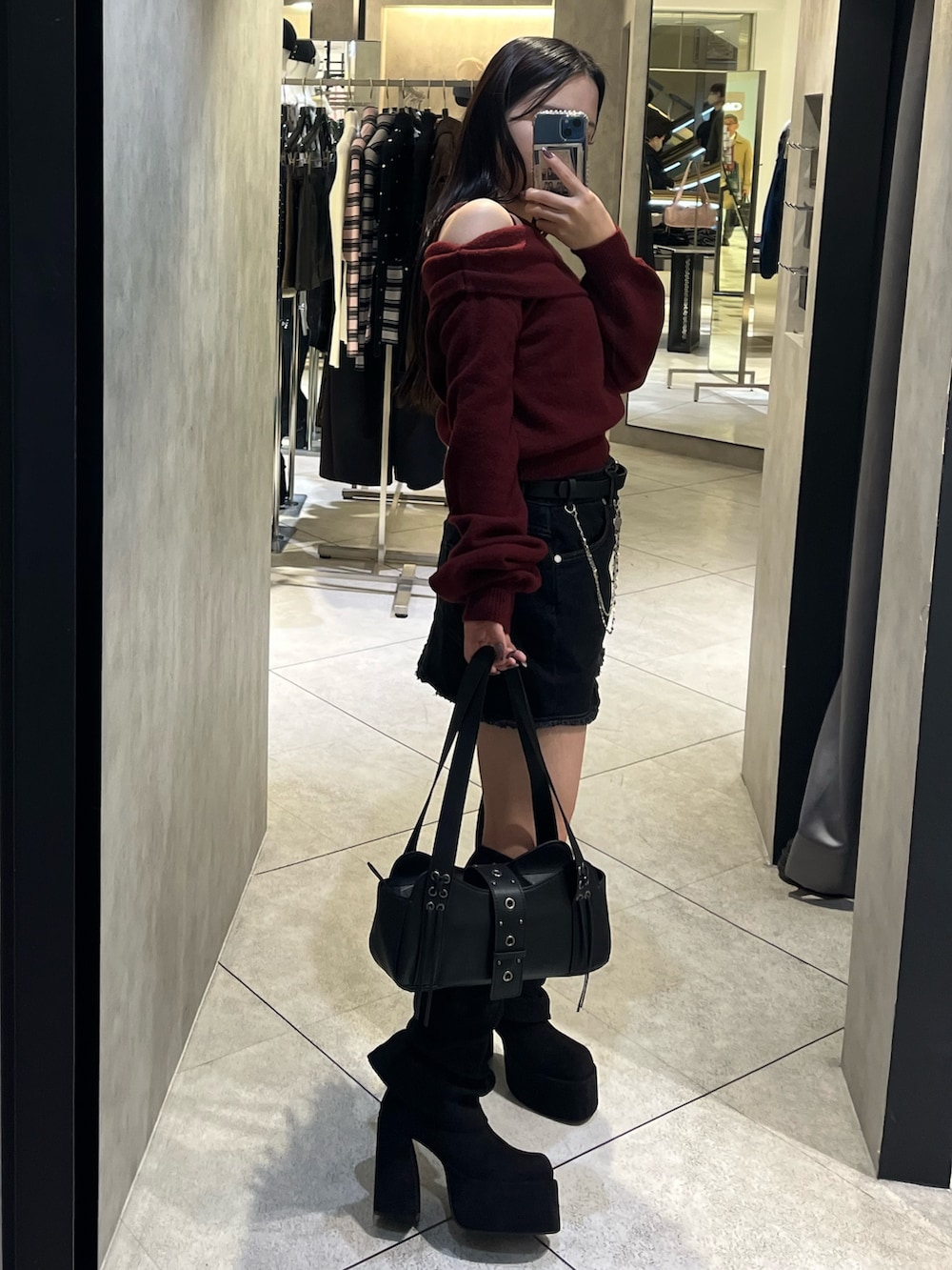 ブラック系のスカート、ブラック系のハンドバッグ、ブラック系のブーツを着用したレディースの秋コーディネートの2枚目の写真