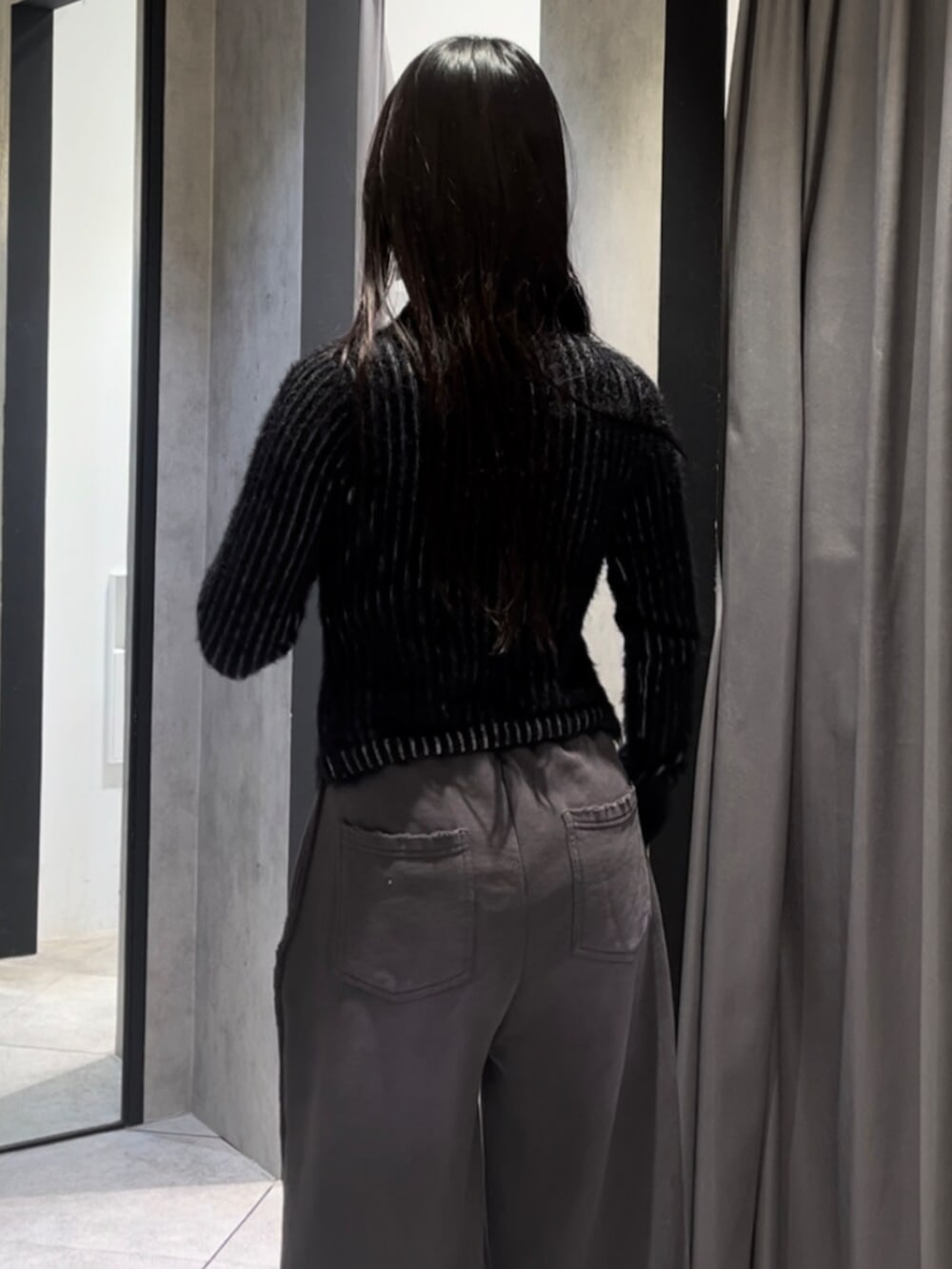 ブラック系のニット/セーター、ホワイト系のショルダーバッグ、ブラック系のブーツを着用したレディースの冬コーディネートの8枚目の写真