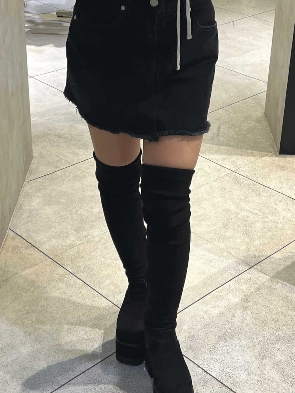 ブラック系のブーツ、グレー系のパーカー、ブラック系のスカートを着用したレディースの秋コーディネートの9枚目の写真