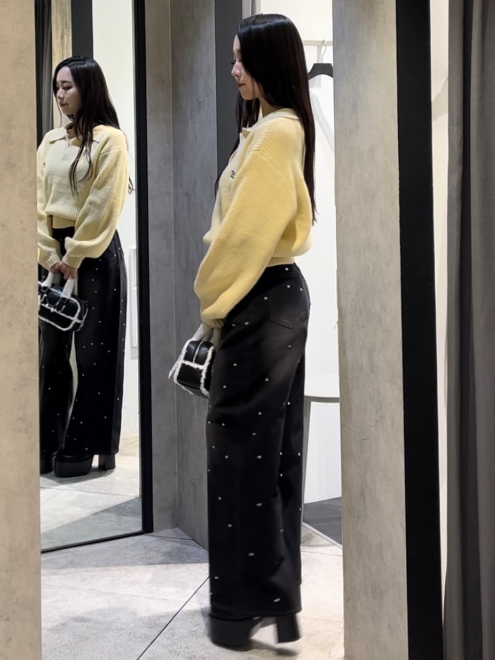 イエロー系のニット/セーター、ブラック系のデニムパンツ、ブラック系のハンドバッグを着用したレディースの冬コーディネートの6枚目の写真