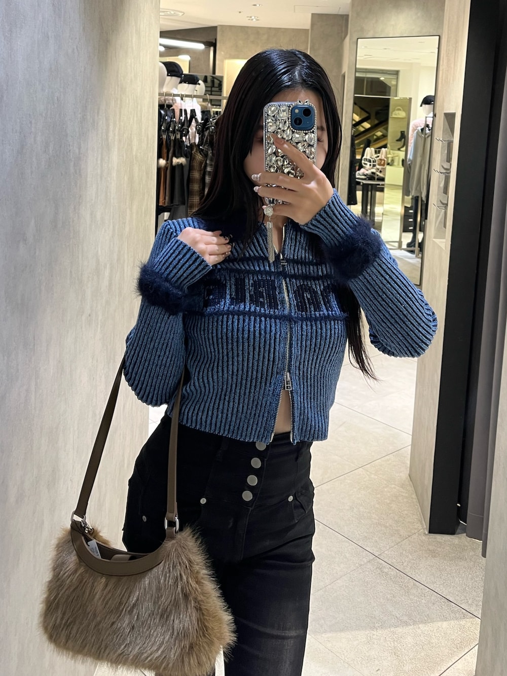 ブルー系のニット/セーター、ブラック系のデニムパンツ、ベージュ系のショルダーバッグを着用したレディースの冬コーディネートの5枚目の写真