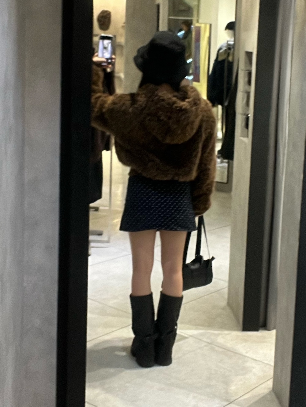 ブラック系のブーツ、ブラック系のハンドバッグ、ブルー系のスカートを着用したレディースの秋コーディネートの3枚目の写真