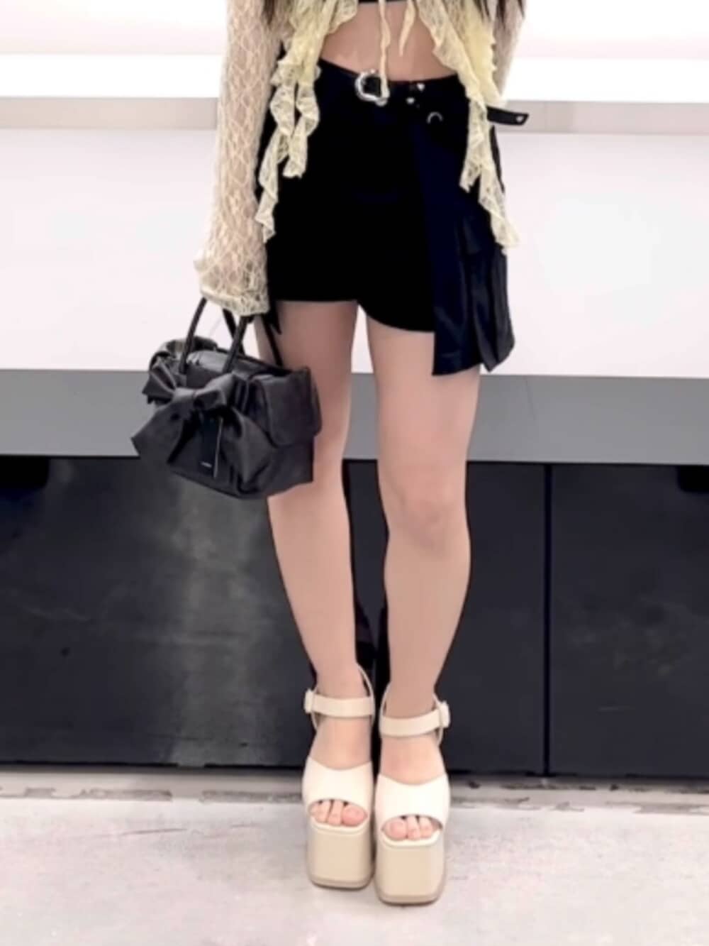 ブラック系のハンドバッグ、ブラック系のスカート、イエロー系のTシャツ/カットソーを着用したレディースの春コーディネートの7枚目の写真