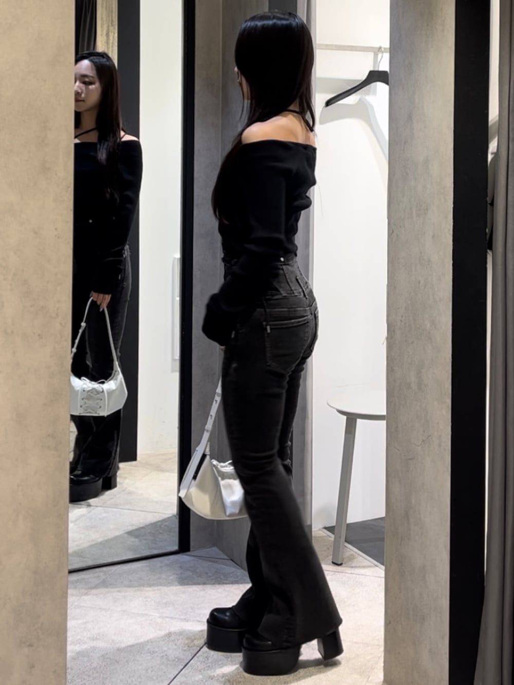 ブラック系のニット/セーター、ブラック系のデニムパンツ、ホワイト系のショルダーバッグを着用したレディースの冬コーディネートの3枚目の写真