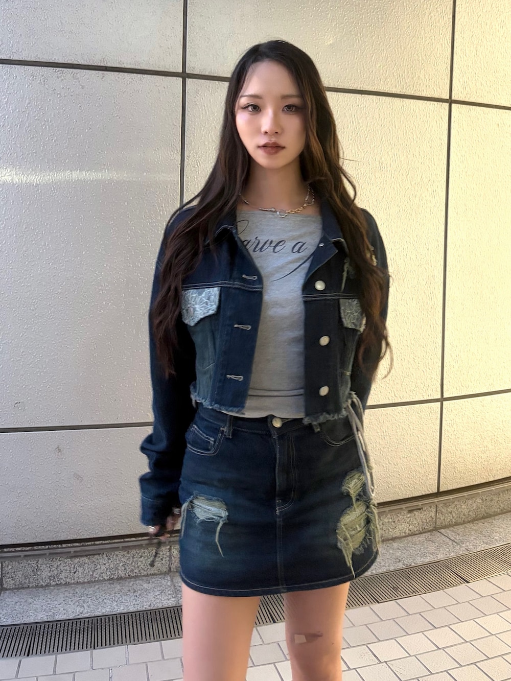 ブルー系のスカート、ブラック系のブーツ、グレー系のTシャツ/カットソーを着用したレディースの秋コーディネートの6枚目の写真