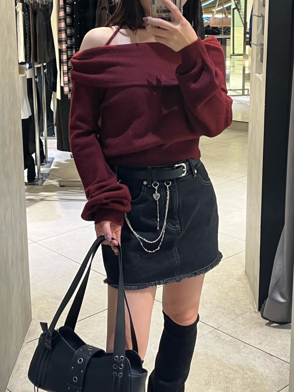 ブラック系のスカート、ブラック系のハンドバッグ、ブラック系のブーツを着用したレディースの秋コーディネートの7枚目の写真