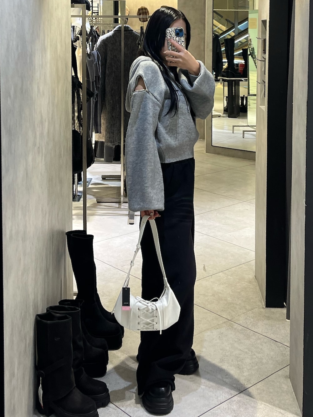 グレー系のパーカー、ブラック系のローファー、ホワイト系のショルダーバッグを着用したレディースの冬コーディネートの3枚目の写真