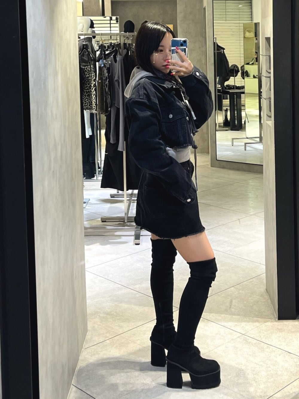 ブラック系のブーツ、グレー系のパーカー、ブラック系のスカートを着用したレディースの秋コーディネートの2枚目の写真