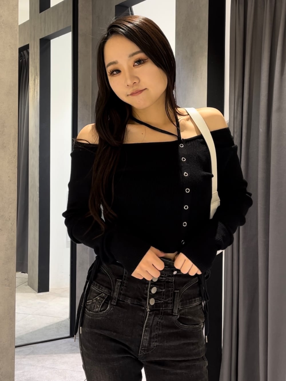 ブラック系のニット/セーター、ブラック系のデニムパンツ、ホワイト系のショルダーバッグを着用したレディースの冬コーディネートの7枚目の写真