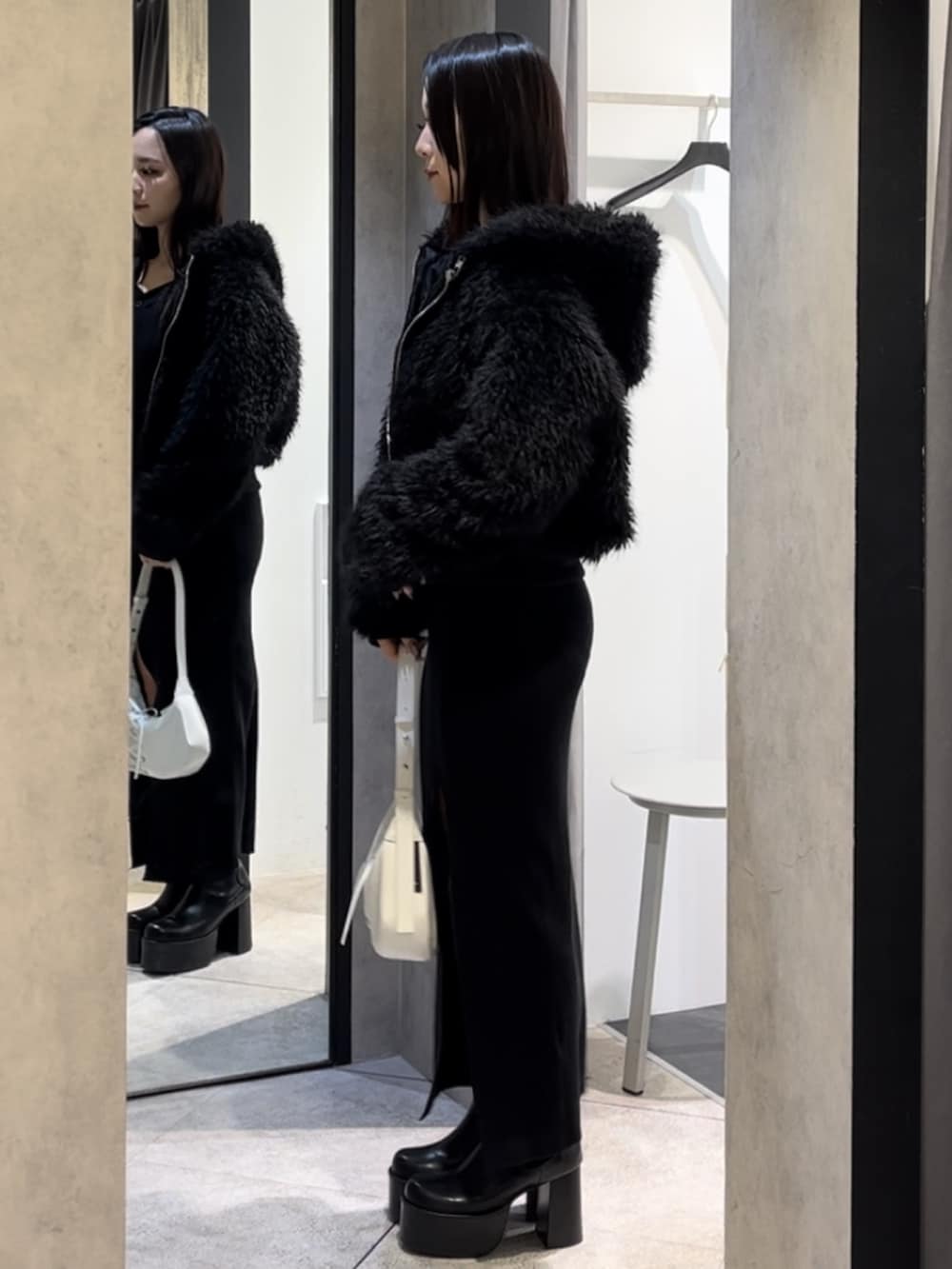 ブラック系のブルゾン、ブラック系のワンピース、ホワイト系のショルダーバッグを着用したレディースの冬コーディネートの2枚目の写真