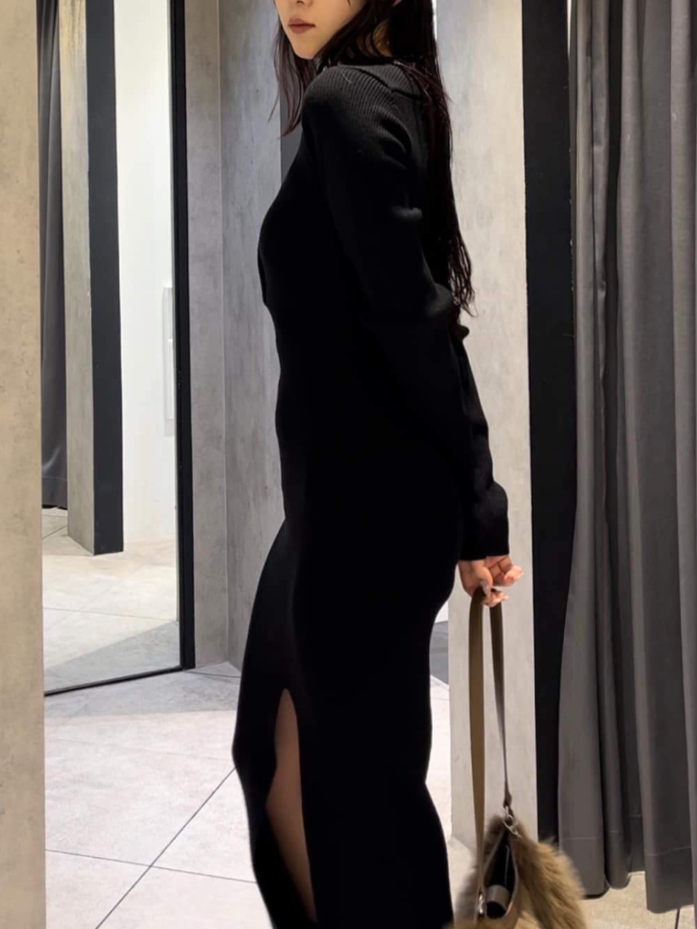 ブラック系のワンピース、ベージュ系のショルダーバッグ、ブラック系のブーツを着用したレディースの冬コーディネートの7枚目の写真