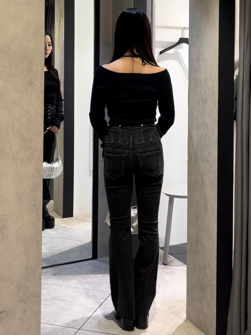 ブラック系のニット/セーター、ブラック系のデニムパンツ、ホワイト系のショルダーバッグを着用したレディースの冬コーディネートの4枚目の写真