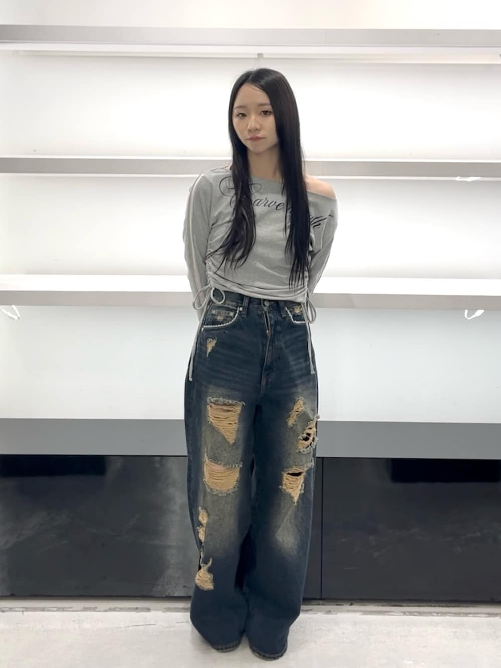 グレー系のTシャツ/カットソー、ブルー系のデニムパンツ、ホワイト系のスニーカーを着用したレディースの春コーディネートの2枚目の写真