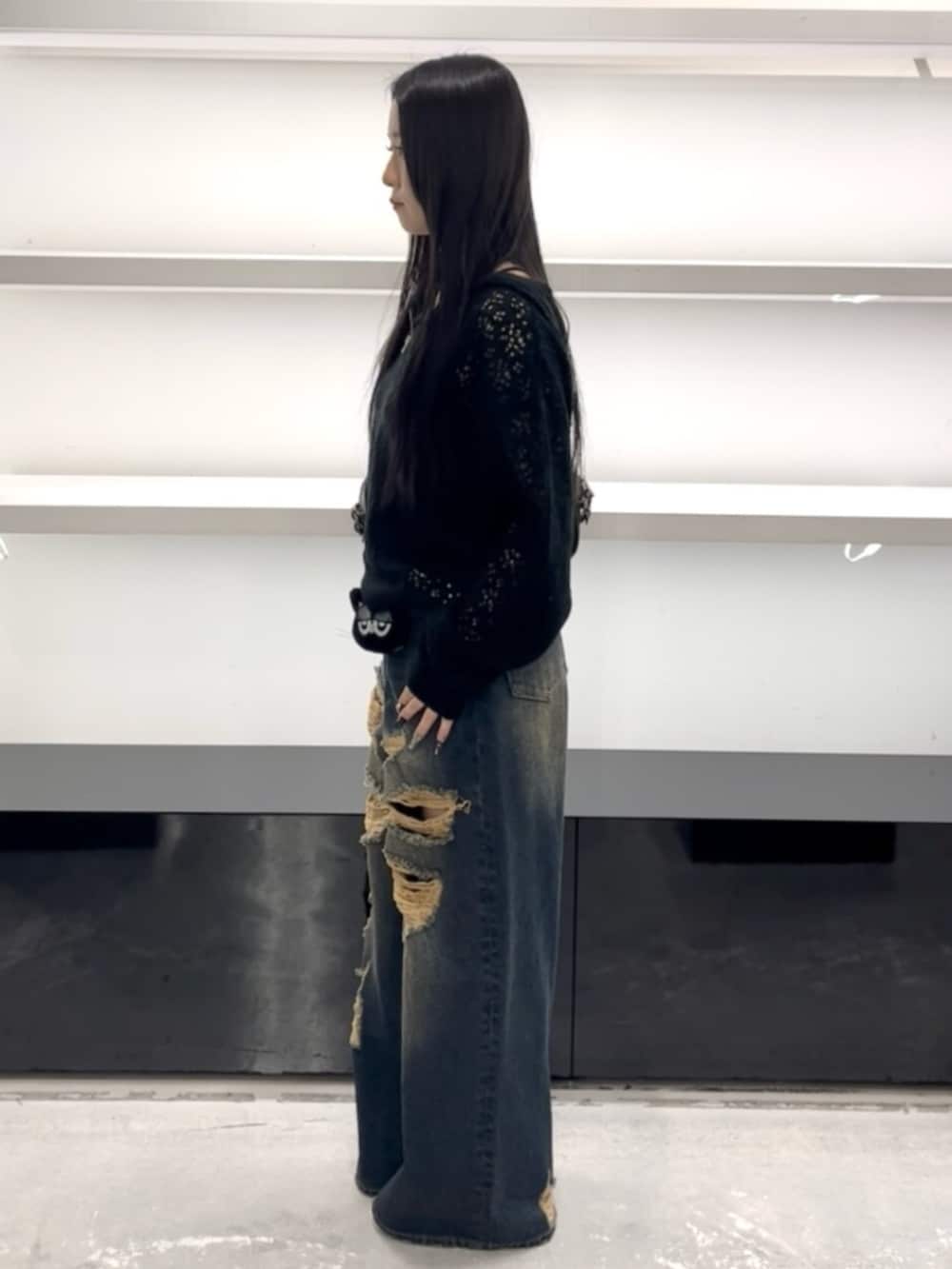 ホワイト系のスニーカー、ブルー系のデニムパンツ、ブラック系のパーカーを着用したレディースの春コーディネートの2枚目の写真