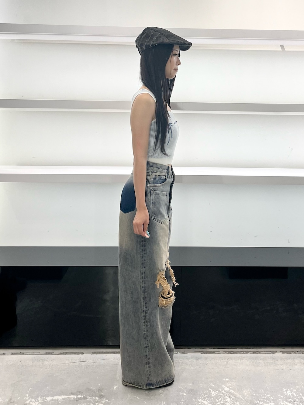 ブルー系のデニムパンツ、ブラック系のサンダル、ブラウン系のハンチング/ベレー帽を着用したレディースの夏コーディネートの3枚目の写真