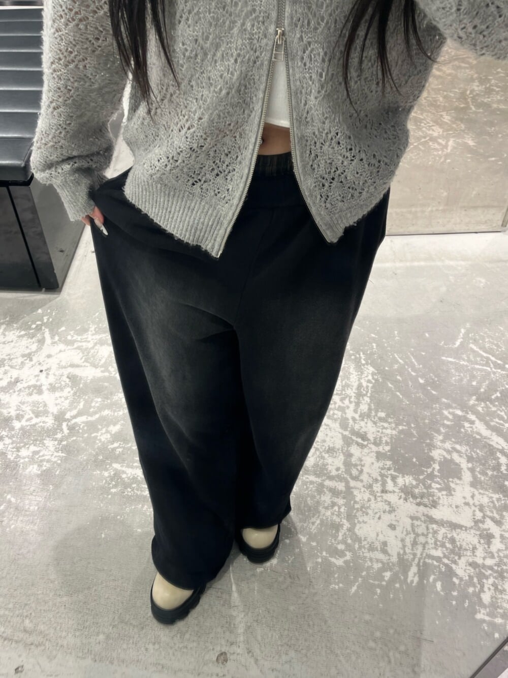 グレー系のパーカー、ブラック系のスウェットパンツ、ホワイト系のニット/セーターを着用したレディースの春コーディネートの7枚目の写真