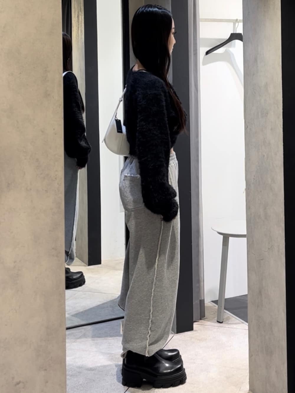 ブラック系のニット/セーター、グレー系のスウェットパンツ、ホワイト系のショルダーバッグを着用したレディースの冬コーディネートの2枚目の写真