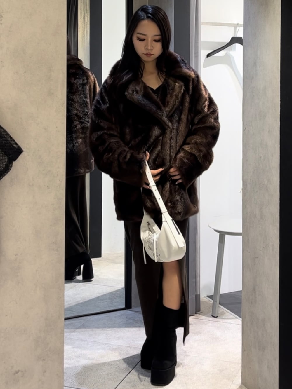 ブラウン系のその他アウター、ホワイト系のショルダーバッグ、ブラック系のブーツを着用したレディースの冬コーディネートの8枚目の写真