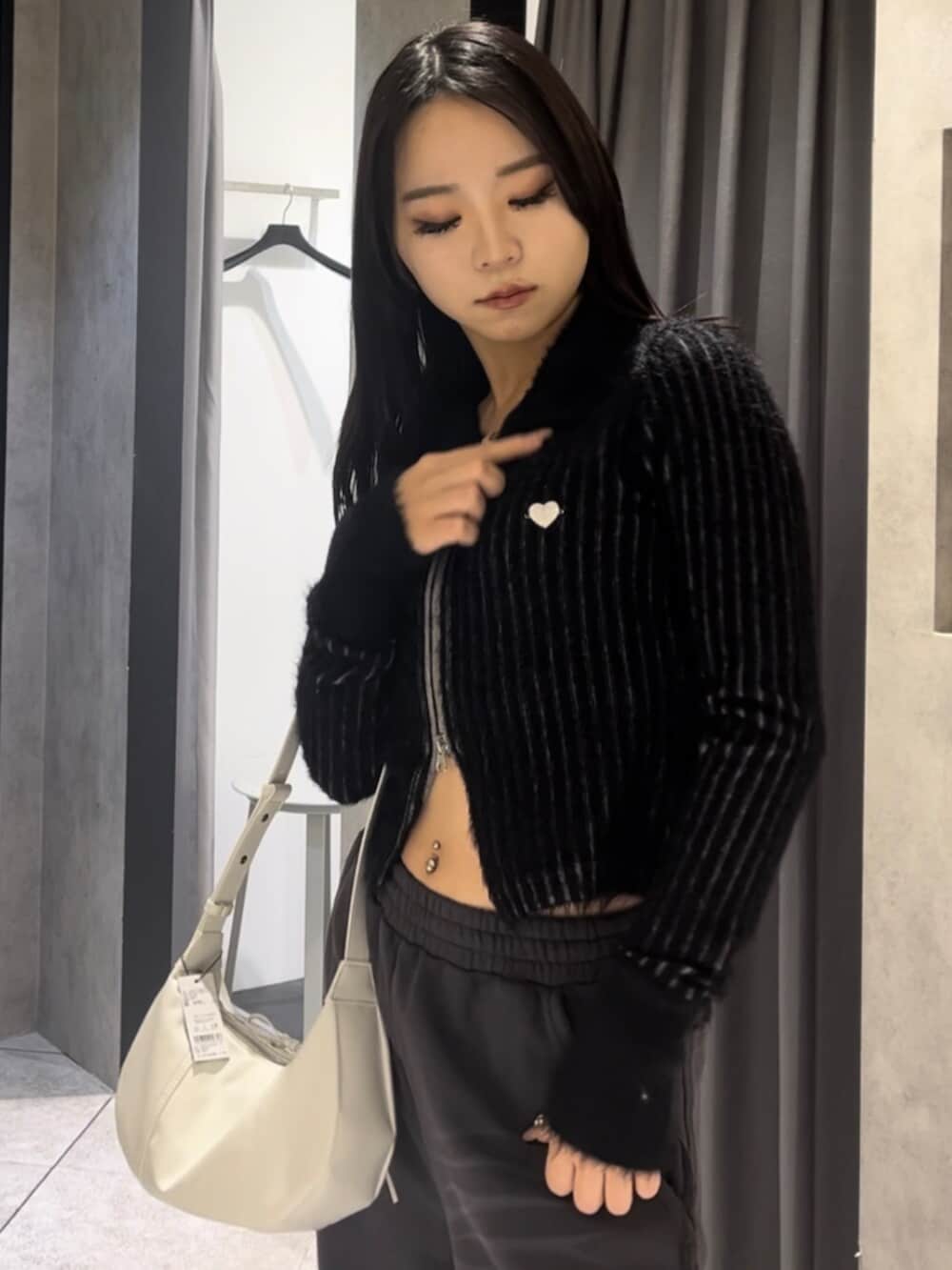 ブラック系のニット/セーター、ホワイト系のショルダーバッグ、ブラック系のブーツを着用したレディースの冬コーディネートの5枚目の写真