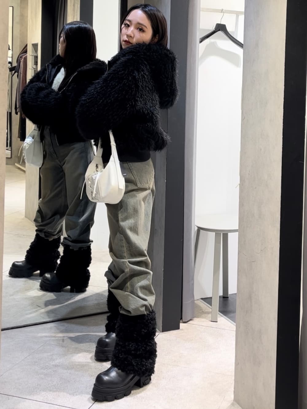 ブラック系のブルゾン、ホワイト系のニット/セーター、ブルー系のデニムパンツを着用したレディースの冬コーディネートの3枚目の写真