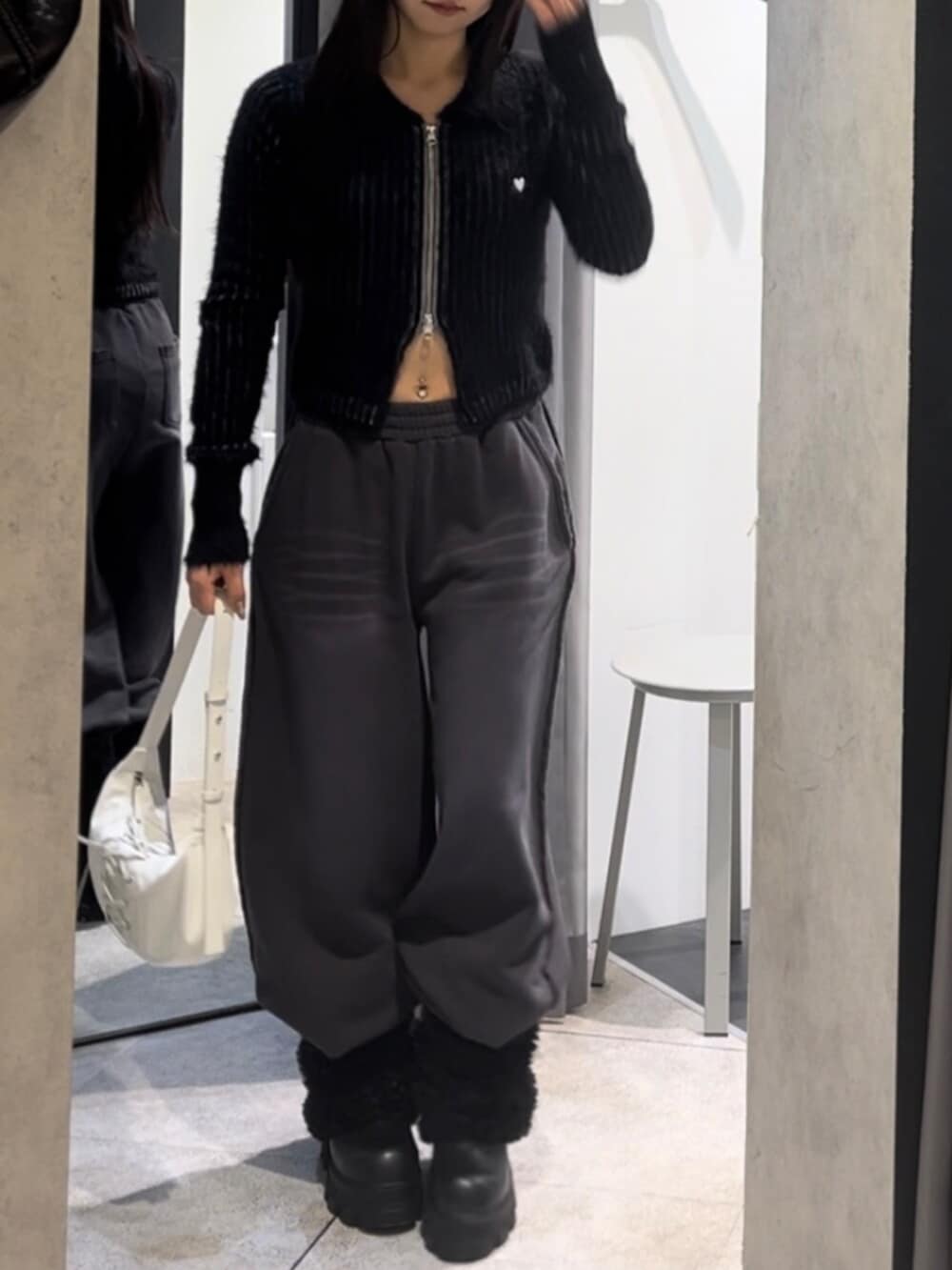 ブラック系のニット/セーター、ホワイト系のショルダーバッグ、ブラック系のブーツを着用したレディースの冬コーディネートの10枚目の写真