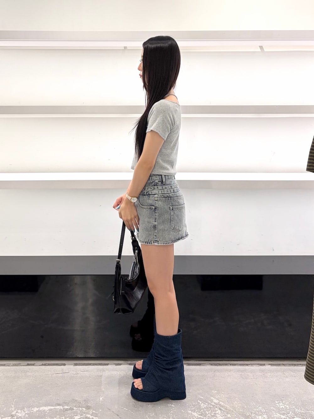 ブルー系のスカート、ブラック系のハンドバッグ、ブルー系のサンダルを着用したレディースの夏コーディネートの4枚目の写真