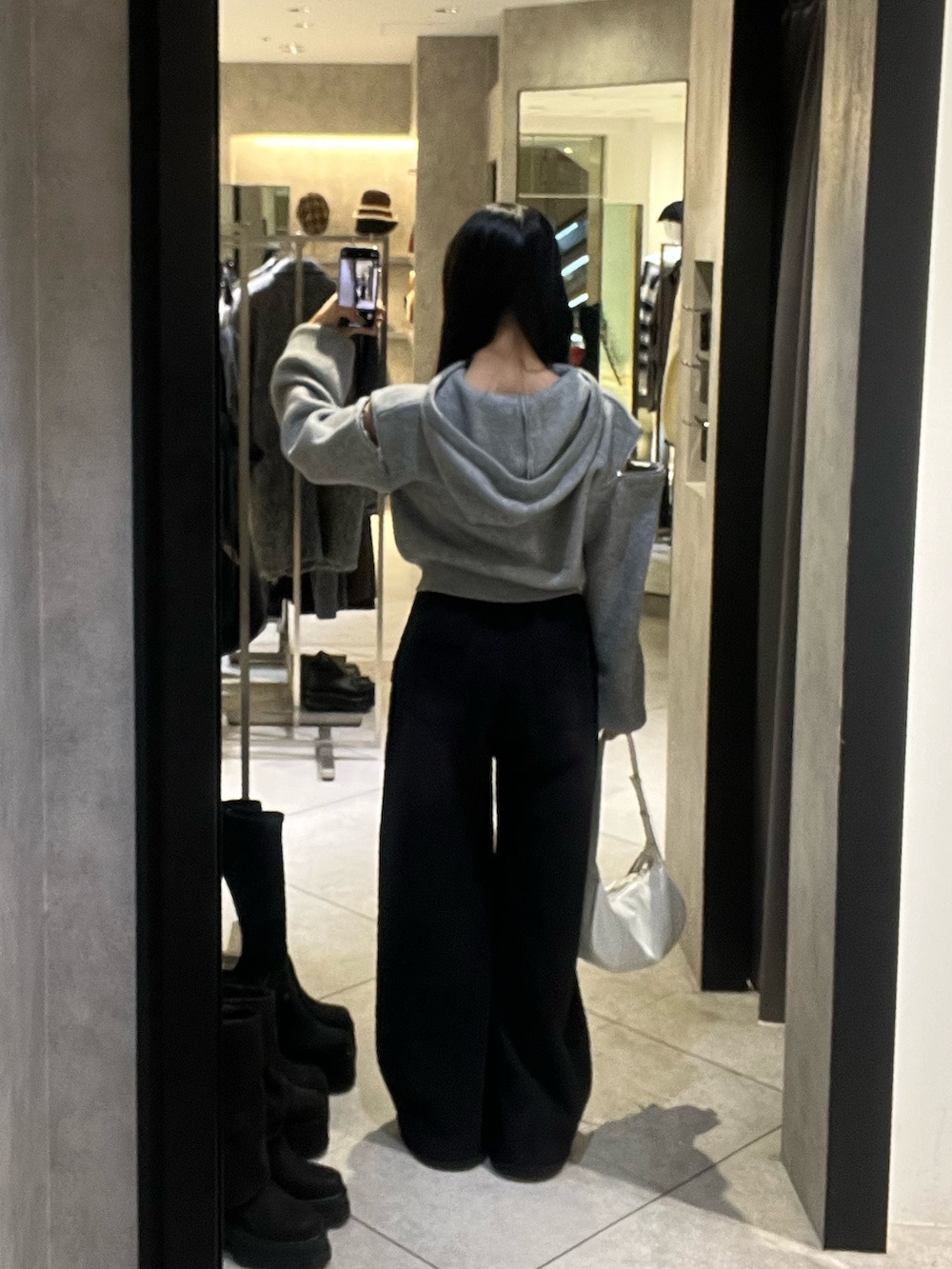 グレー系のパーカー、ブラック系のローファー、ホワイト系のショルダーバッグを着用したレディースの冬コーディネートの4枚目の写真