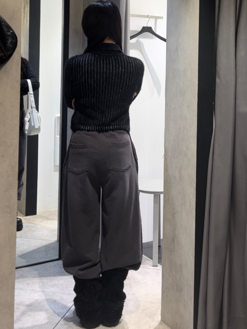 ブラック系のニット/セーター、ホワイト系のショルダーバッグ、ブラック系のブーツを着用したレディースの冬コーディネートの3枚目の写真