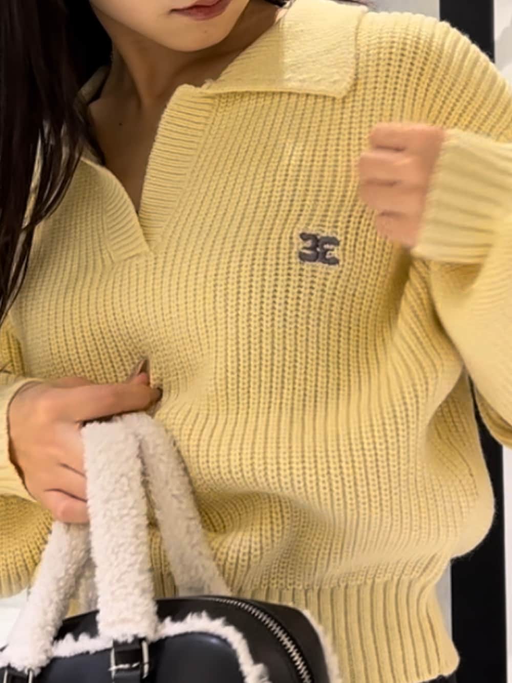 イエロー系のニット/セーター、ブラック系のデニムパンツ、ブラック系のハンドバッグを着用したレディースの冬コーディネートの7枚目の写真