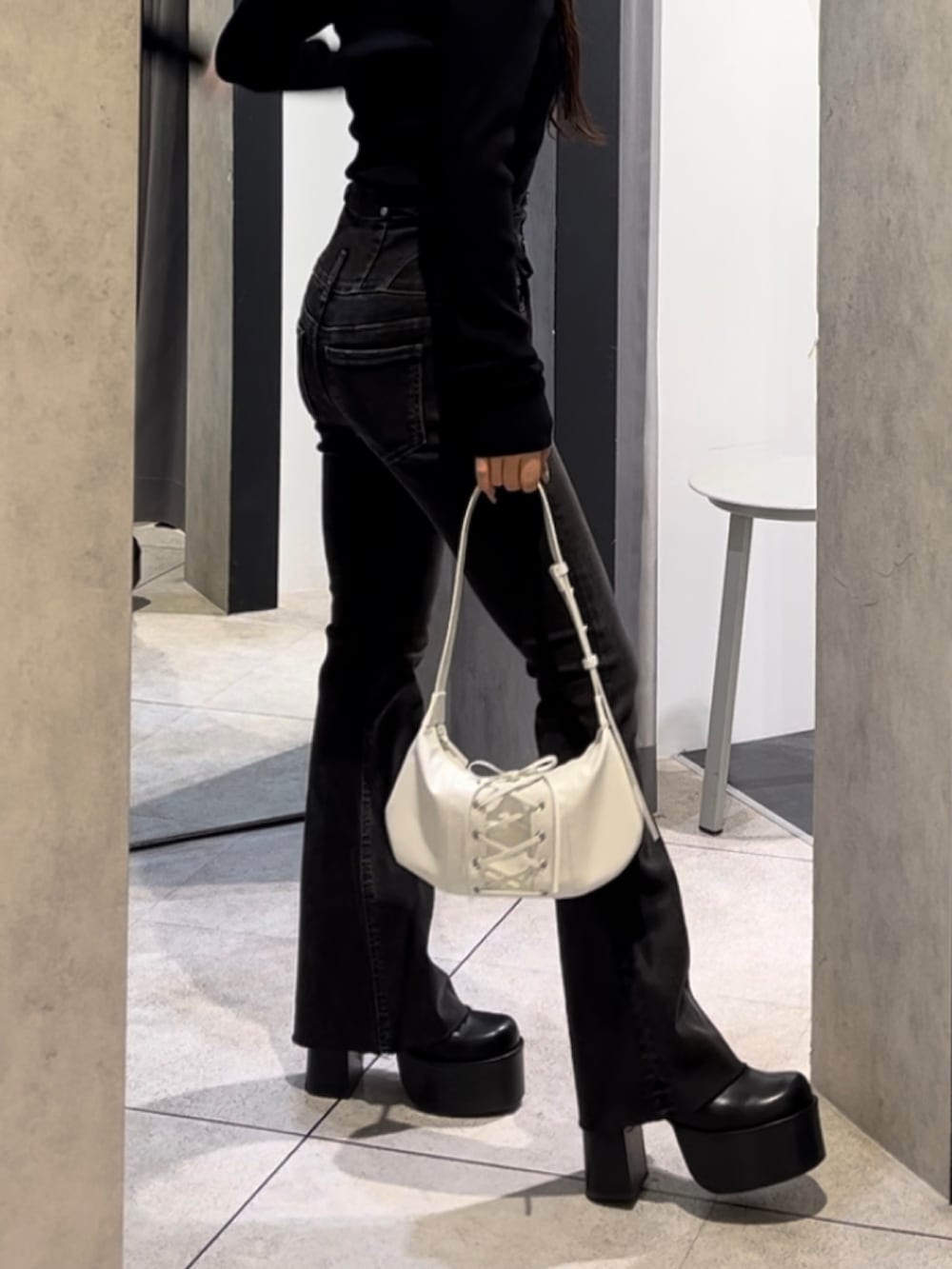 ブラック系のニット/セーター、ブラック系のデニムパンツ、ホワイト系のショルダーバッグを着用したレディースの冬コーディネートの10枚目の写真