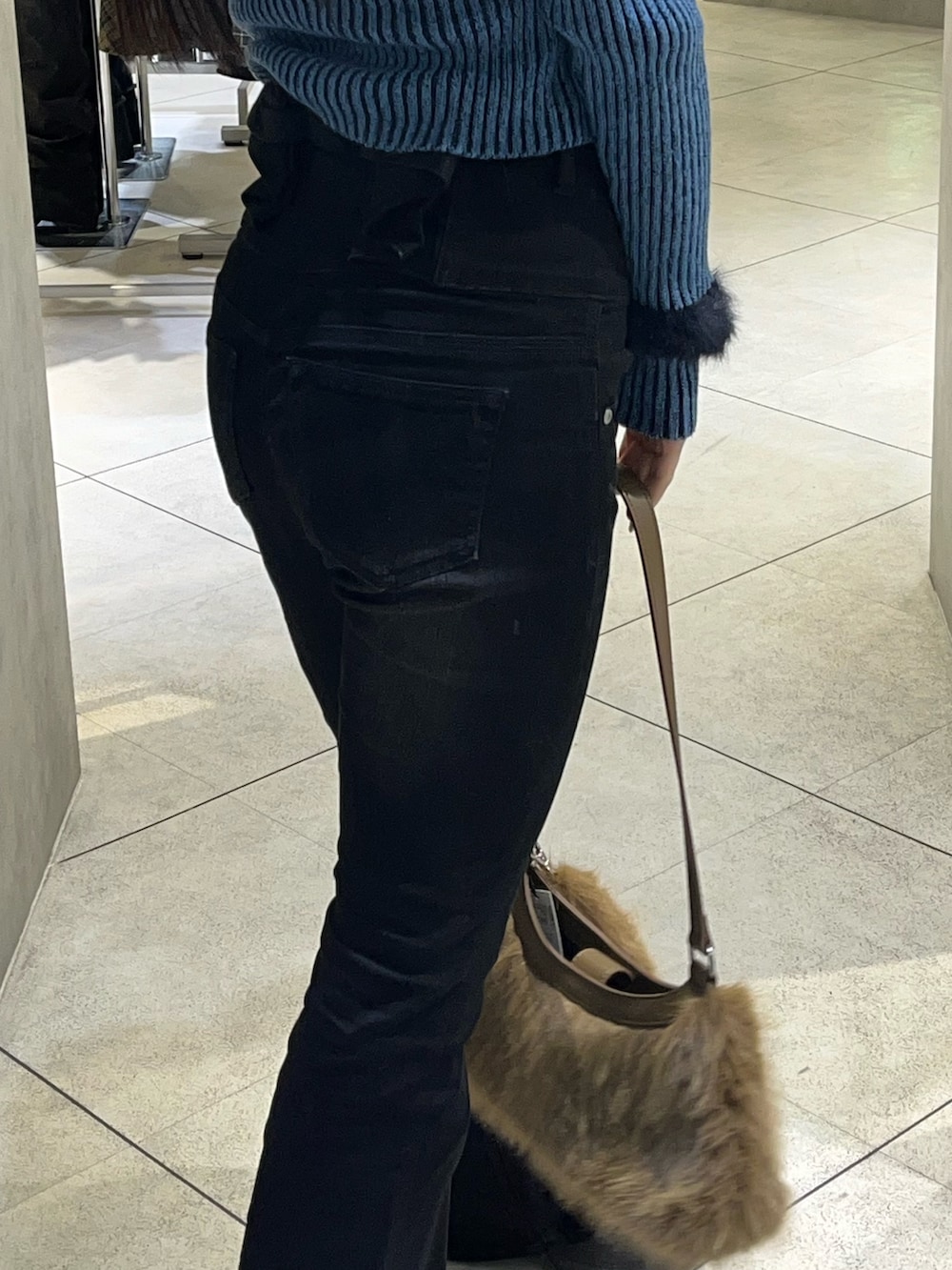 ブルー系のニット/セーター、ブラック系のデニムパンツ、ベージュ系のショルダーバッグを着用したレディースの冬コーディネートの7枚目の写真