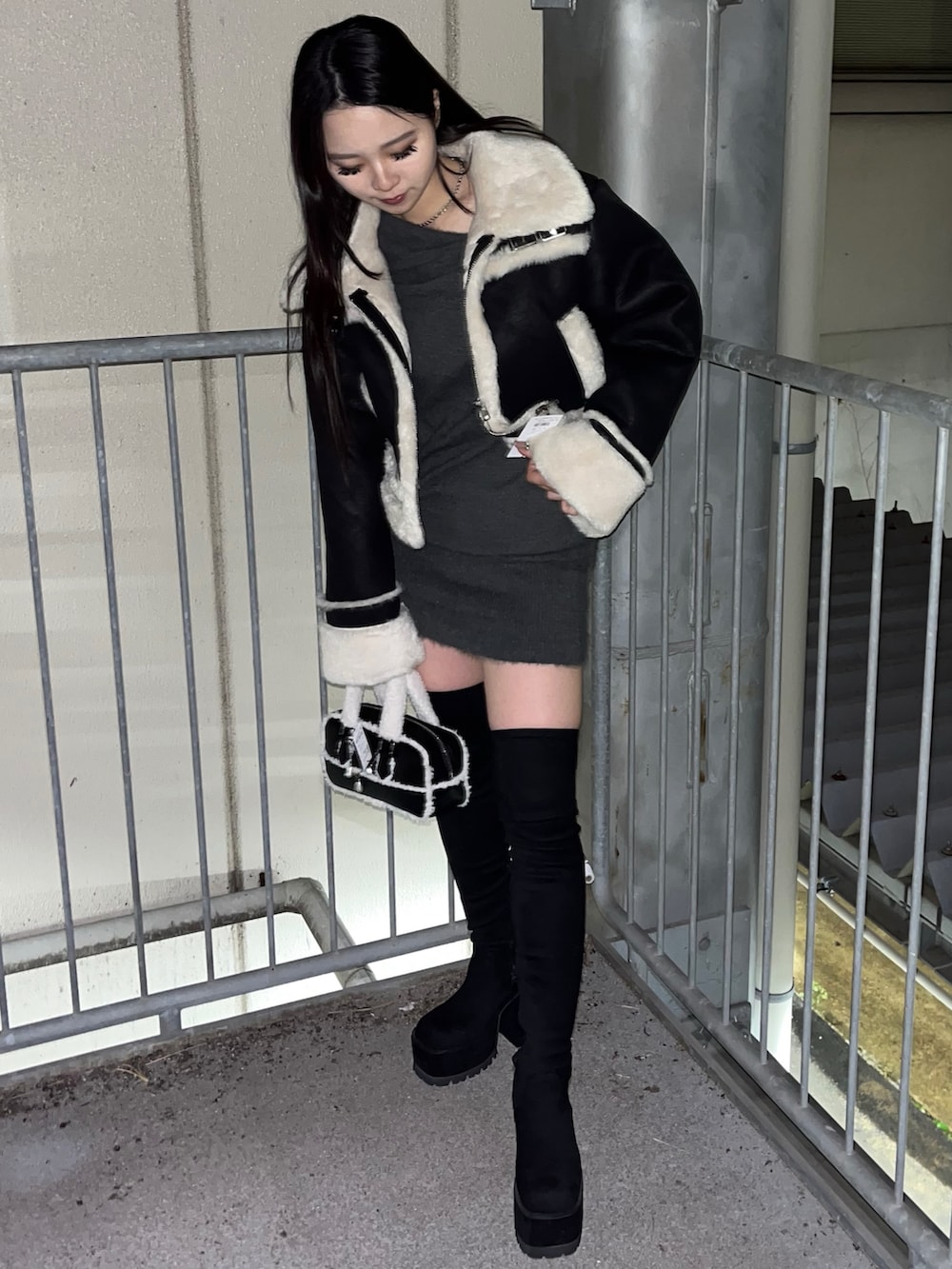 ブラック系のブルゾン、グレー系のワンピース、ブラック系のハンドバッグを着用したレディースの冬コーディネートの3枚目の写真