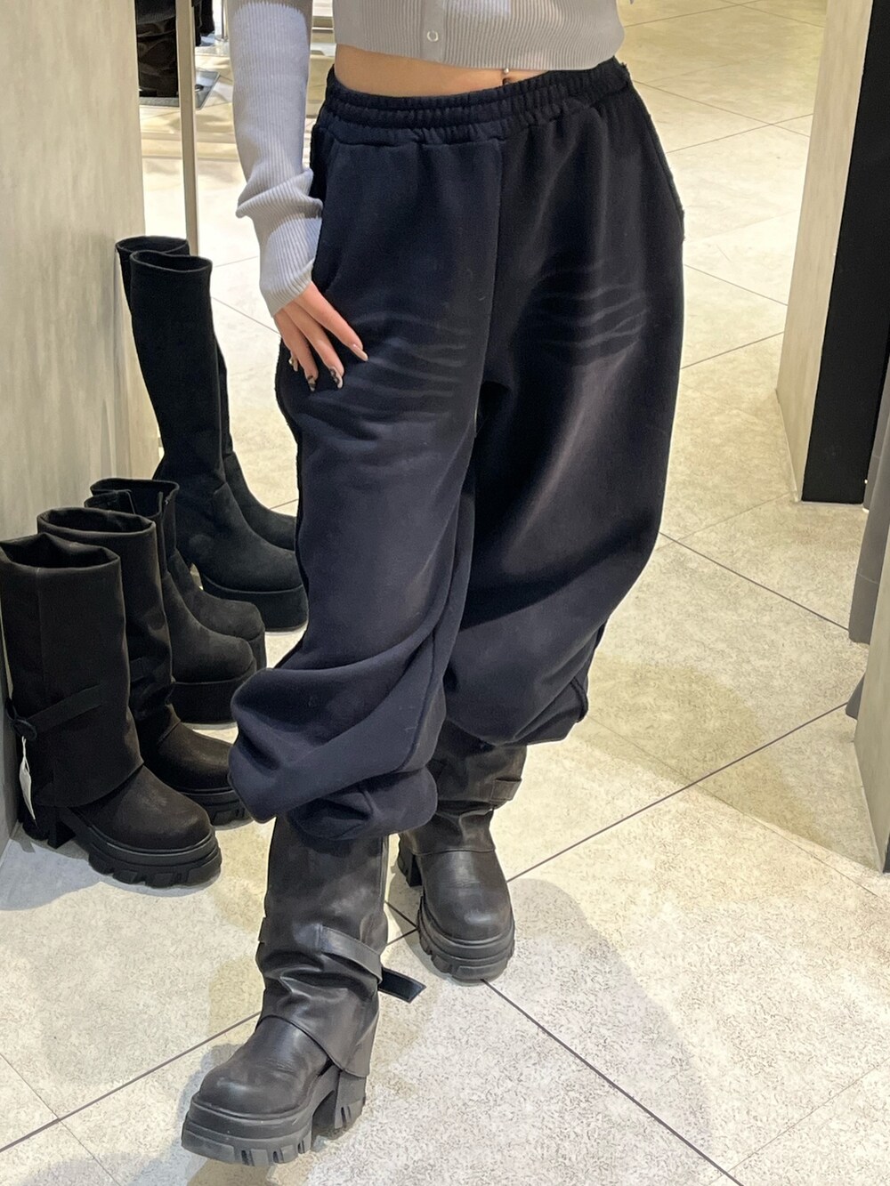 グレー系のニット/セーター、ブラック系のスウェットパンツ、ブラック系のブーツを着用したレディースの冬コーディネートの9枚目の写真