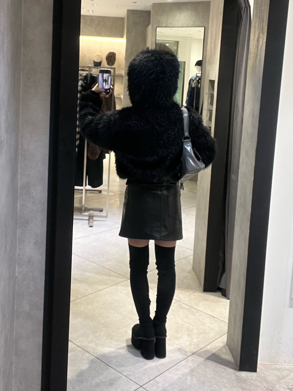 ブラック系のブーツ、グレー系のハンドバッグ、ブラック系のスカートを着用したレディースの秋コーディネートの5枚目の写真