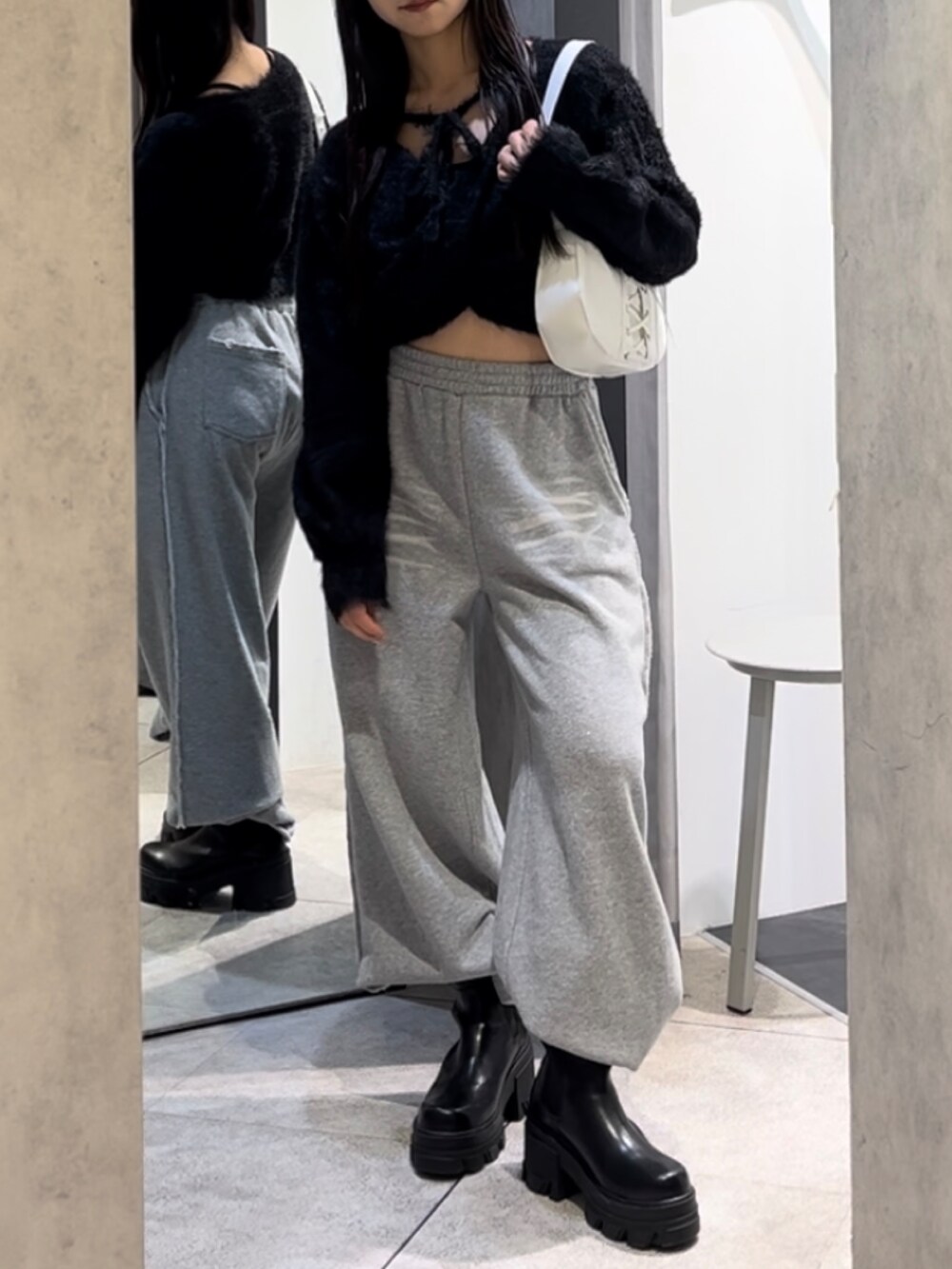 ブラック系のニット/セーター、グレー系のスウェットパンツ、ホワイト系のショルダーバッグを着用したレディースの冬コーディネートの7枚目の写真