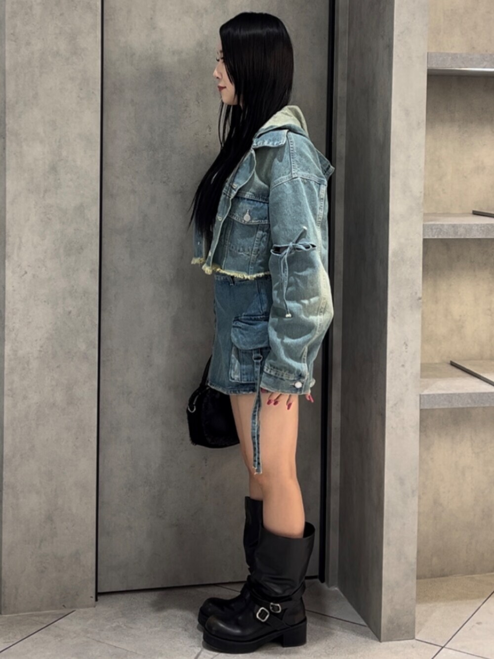 ブラック系のボストンバッグ、ブラック系のブーツ、ブルー系のデニムジャケットを着用したレディースの冬コーディネートの3枚目の写真