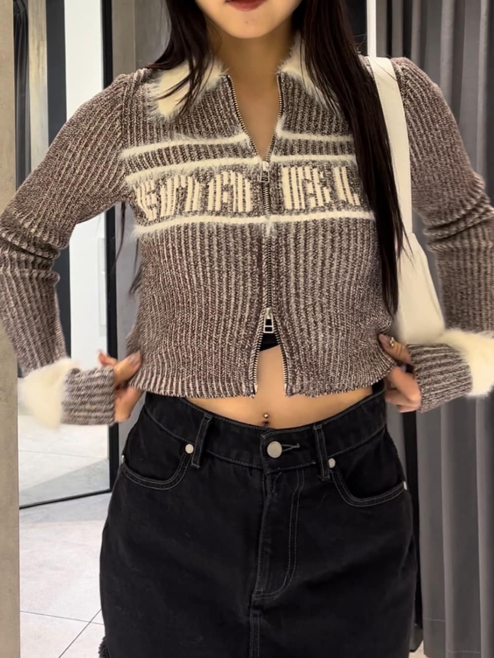 ブラウン系のニット/セーター、ブラック系のスカート、ホワイト系のショルダーバッグを着用したレディースの冬コーディネートの10枚目の写真