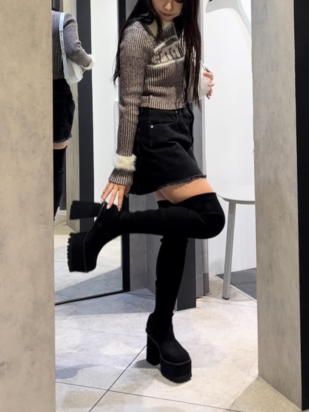 ブラウン系のニット/セーター、ブラック系のスカート、ホワイト系のショルダーバッグを着用したレディースの冬コーディネートの7枚目の写真