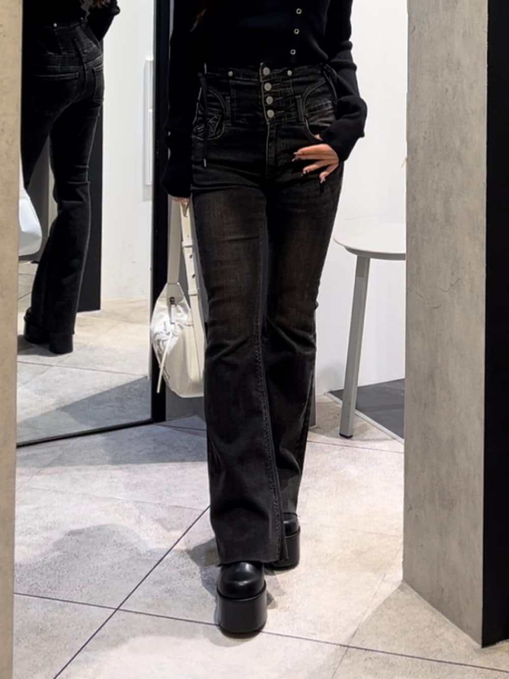 ブラック系のニット/セーター、ブラック系のデニムパンツ、ホワイト系のショルダーバッグを着用したレディースの冬コーディネートの8枚目の写真