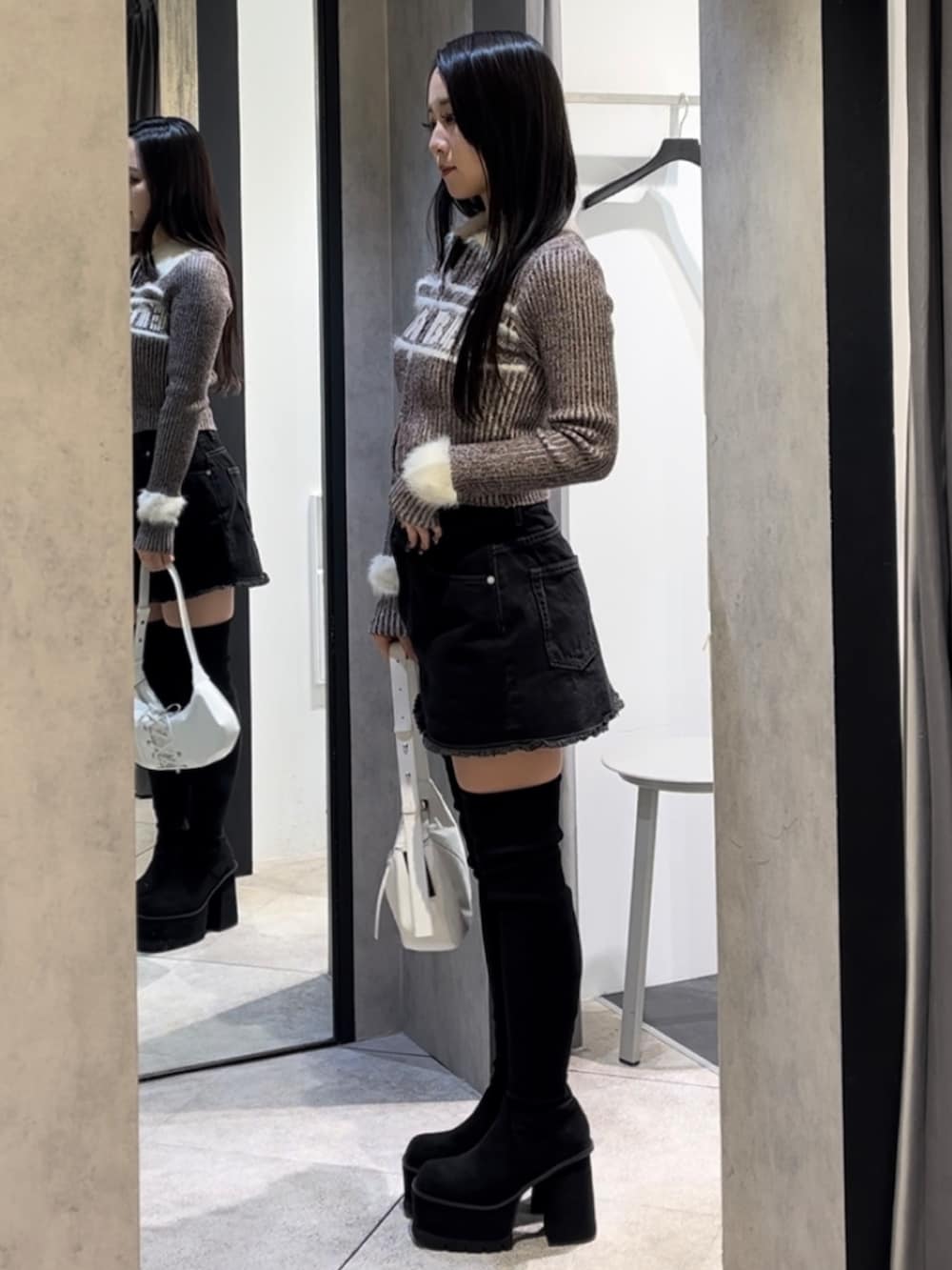 ブラウン系のニット/セーター、ブラック系のスカート、ホワイト系のショルダーバッグを着用したレディースの冬コーディネートの2枚目の写真