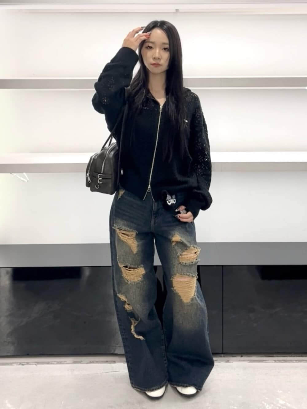 ホワイト系のスニーカー、ブルー系のデニムパンツ、ブラック系のパーカーを着用したレディースの春コーディネートの4枚目の写真