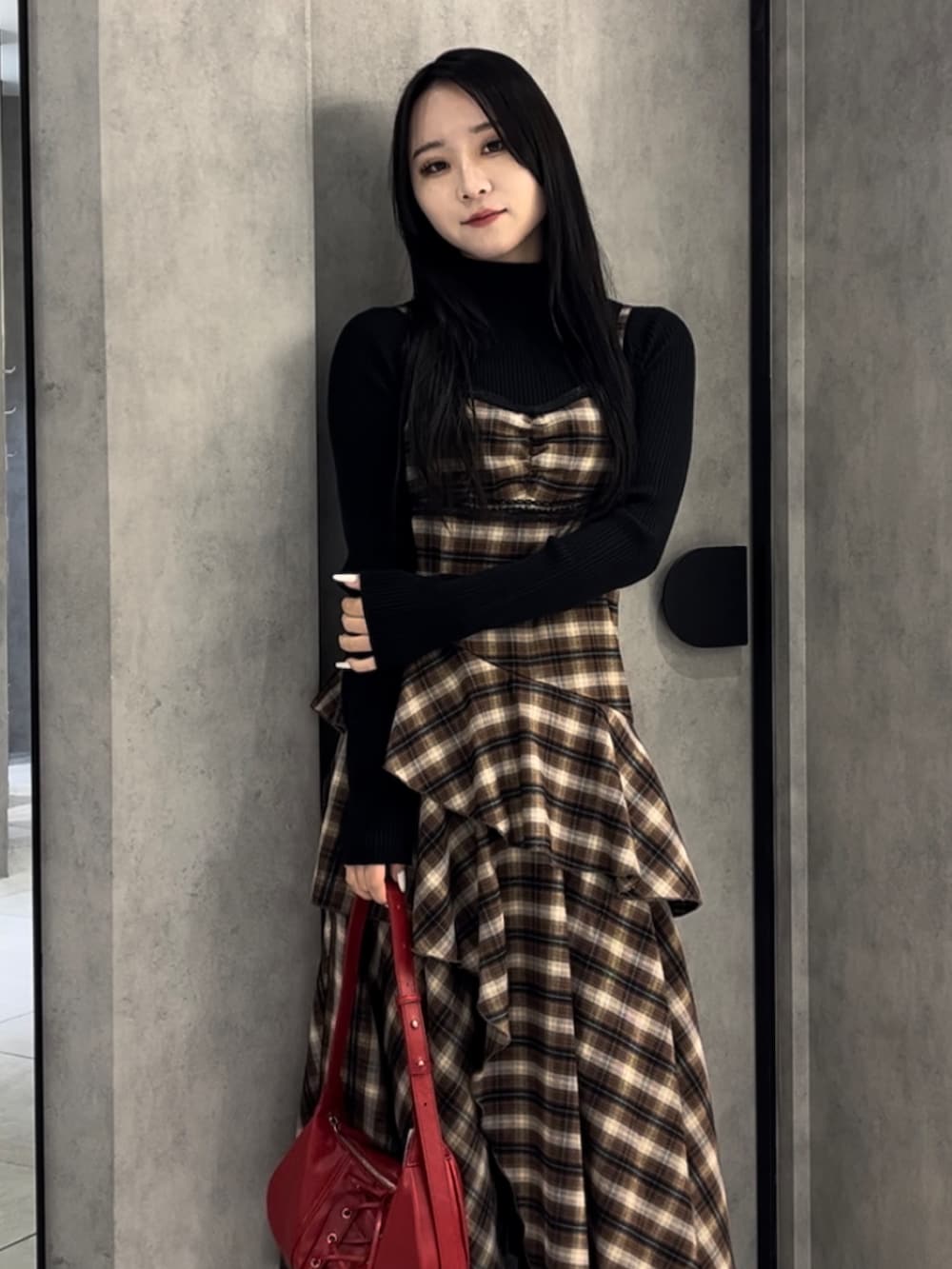 ブラック系のニット/セーター、ベージュ系のワンピース、レッド系のショルダーバッグを着用したレディースの冬コーディネートの5枚目の写真