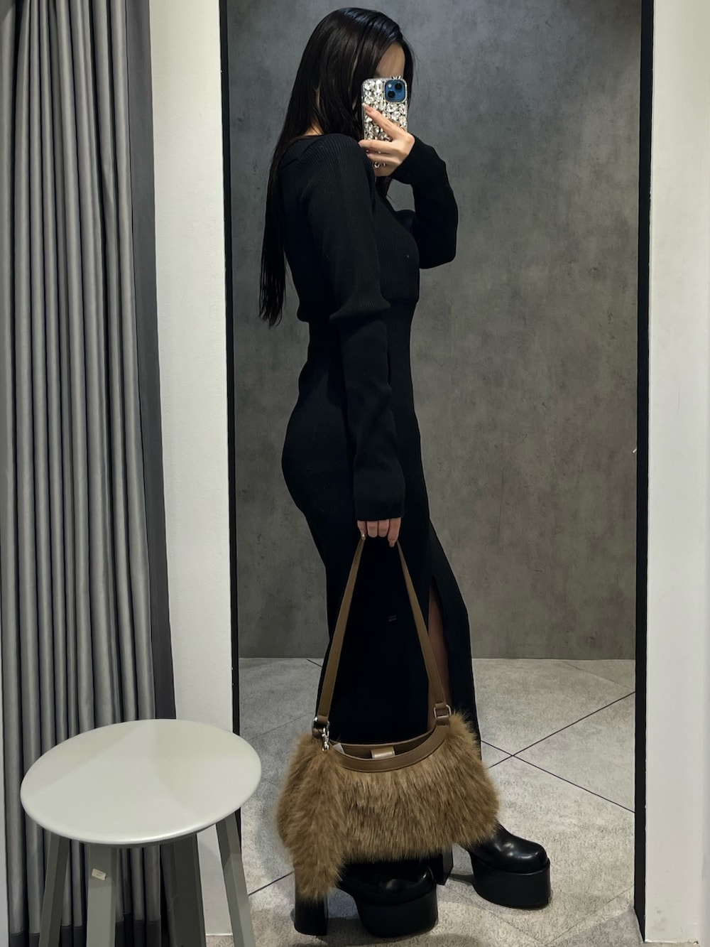 ブラック系のワンピース、ベージュ系のショルダーバッグ、ブラック系のブーツを着用したレディースの冬コーディネートの2枚目の写真