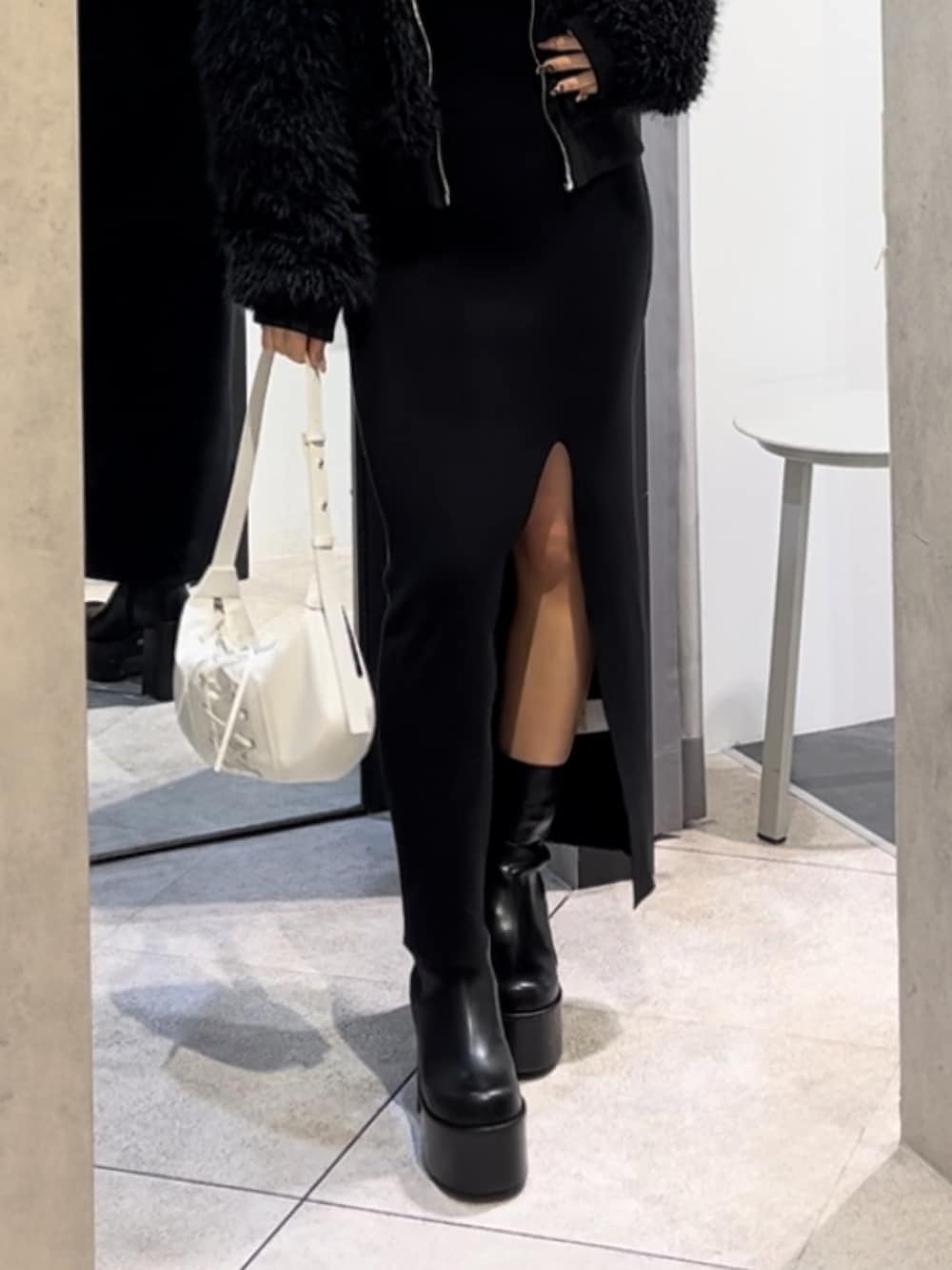 ブラック系のブルゾン、ブラック系のワンピース、ホワイト系のショルダーバッグを着用したレディースの冬コーディネートの9枚目の写真