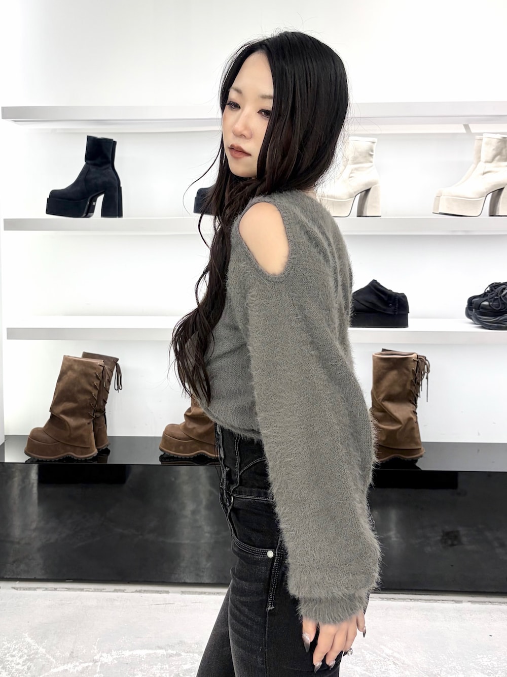 グレー系のニット/セーター、ブラック系のデニムパンツ、ブラック系のショルダーバッグを着用したレディースの秋コーディネートの6枚目の写真