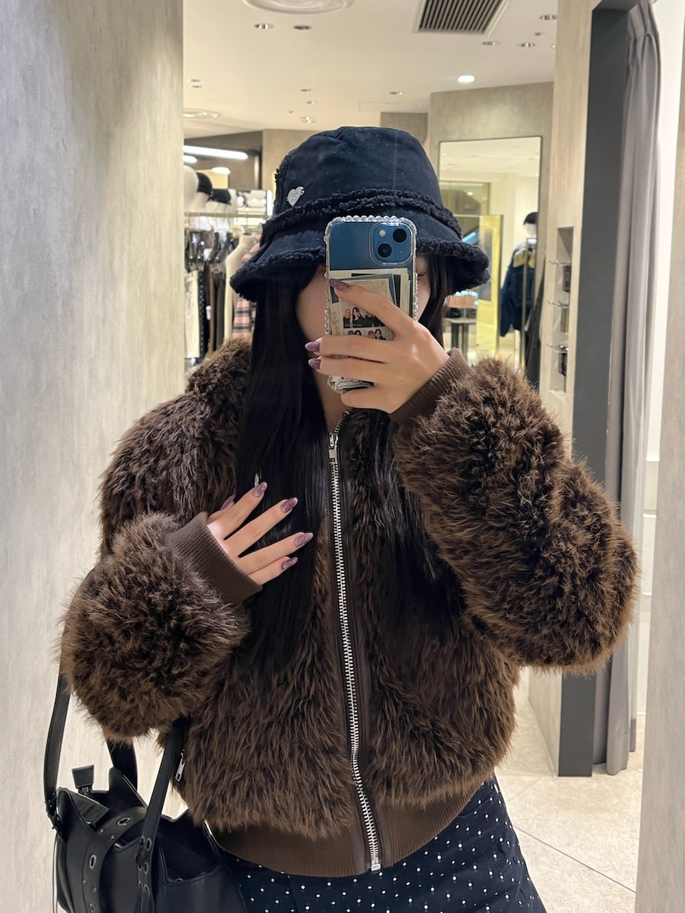 ブラック系のブーツ、ブラック系のハンドバッグ、ブルー系のスカートを着用したレディースの秋コーディネートの4枚目の写真