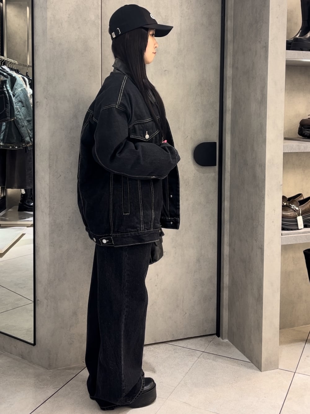 ブルー系のブルゾン、ブルー系のデニムパンツ、ブラック系のハンドバッグを着用したレディースの冬コーディネートの2枚目の写真